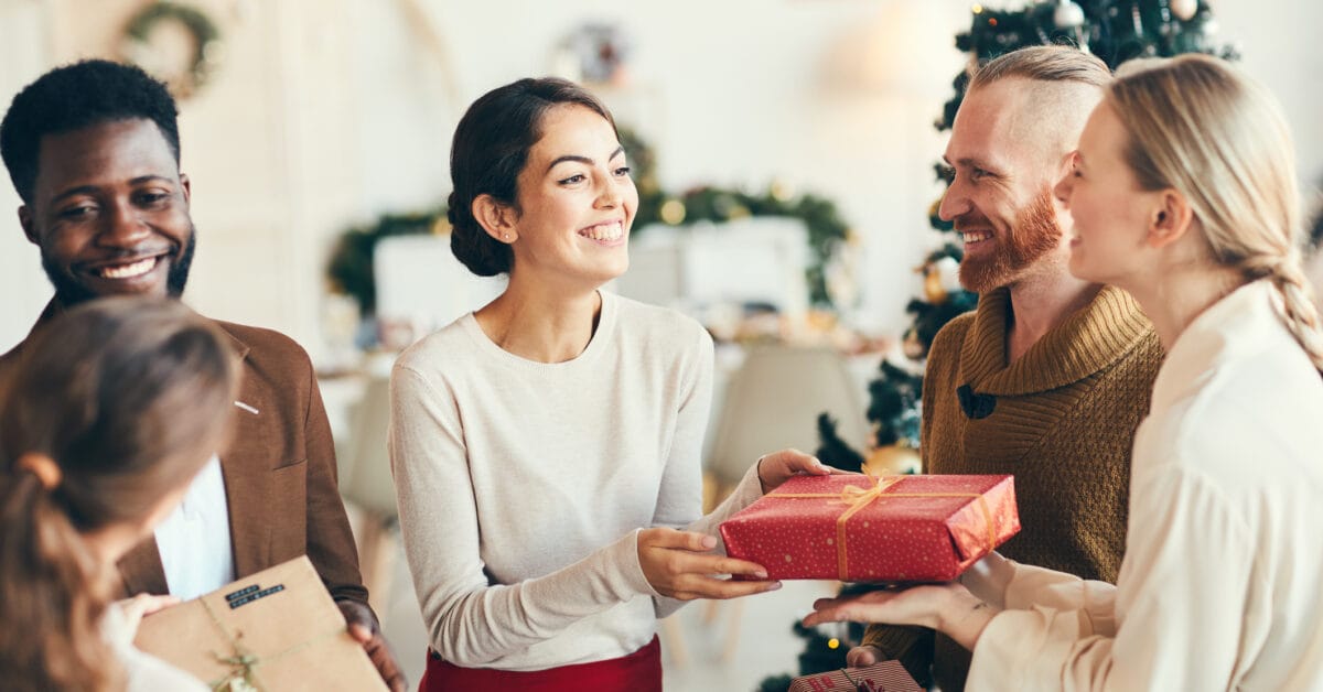 A group of friends exchange presents, proud of the best skincare product Christmas gift ideas they’ve thought of for each other.